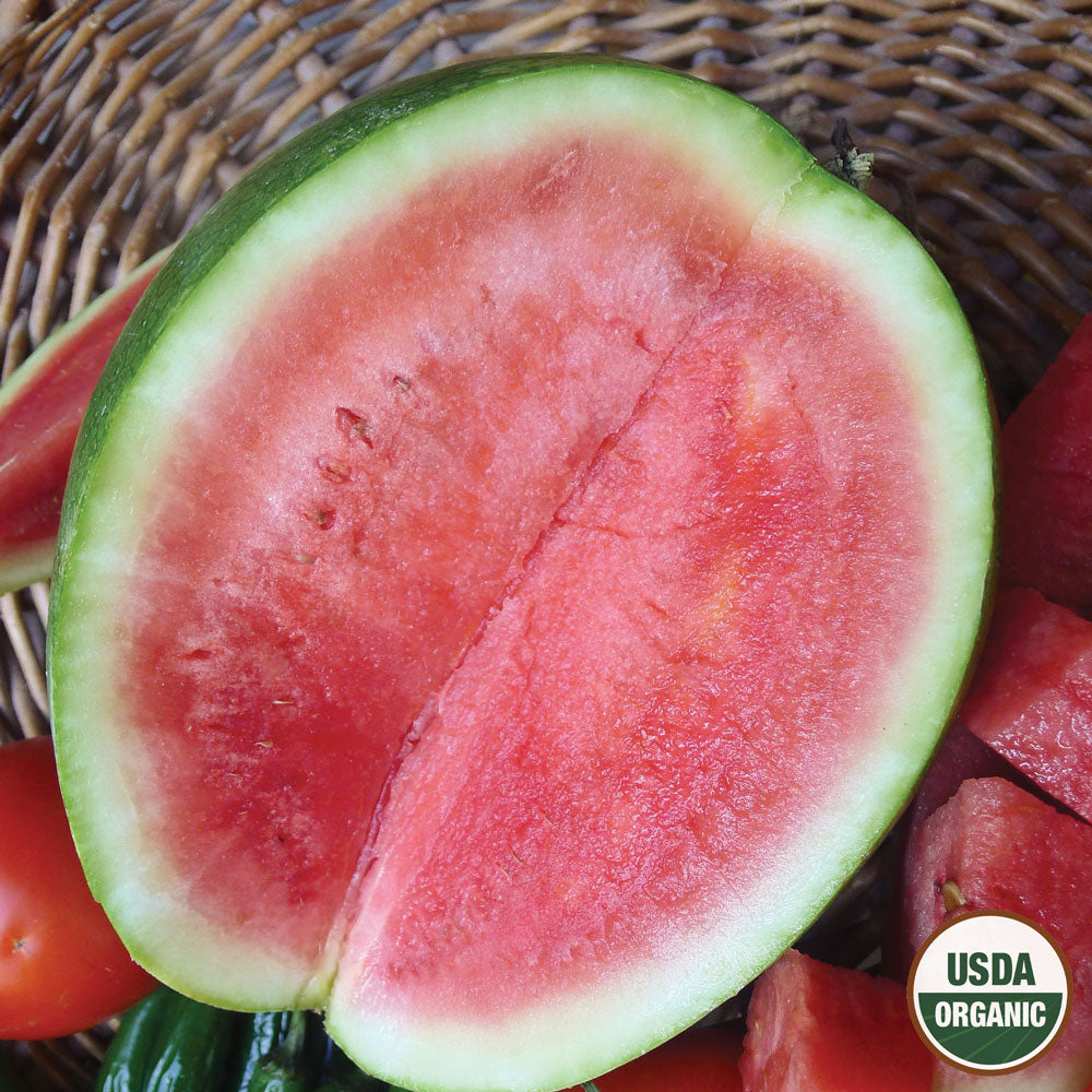A halved watermelon displaying the vibrant red flesh and green skin, with the USDA Organic logo visible.